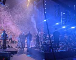 Une équipe technique travaille dans les coulisses de Vibes Concert à la création d'une expérience immersive, avec des techniciens ajustant lumières et écrans.